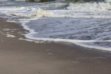 Yumuşak okyanus dalgalarının kumlu sahile ulaşmasını yakından görmek, suyun denize geri çekilmesiyle köpüklü bir iz bırakır..