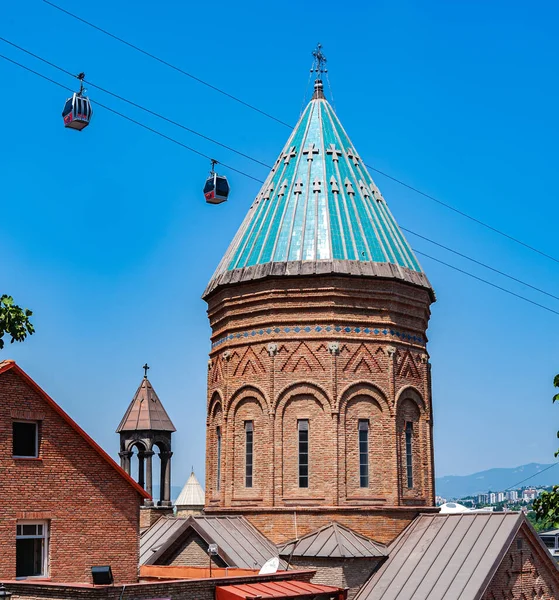 stock image Tbilisi.Church of St. Gevorg against the blue sky.Cable car cabins move near the dome of the temple.Copy space.