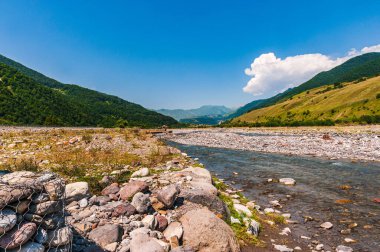 Georgia mı? Yaz güneşli bir gün. Beyaz ve siyah nehir Aragvit vadide akıyor. Dağlar, mavi gökyüzü beyaz bulutlu..