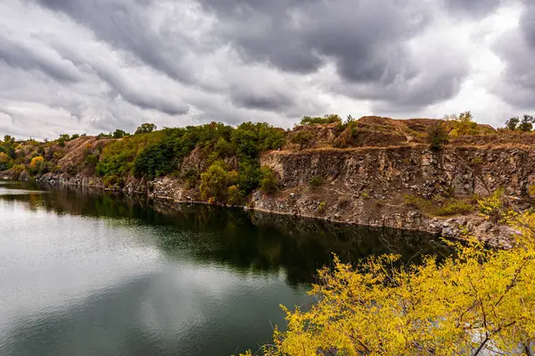 Ukrayna. Bulutlu bir sonbahar günü. Yaşlı Kodak. Granit ocağı suyla dolmuş. Bulutlu gökyüzü. Boşluğu kopyala.