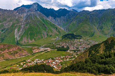 Stepantsminda, Saint Stepan, Kazak Dağı eteklerinde bulunan bir köydür. Dağ sırası. Mavi gökyüzü beyaz bulutlarda..