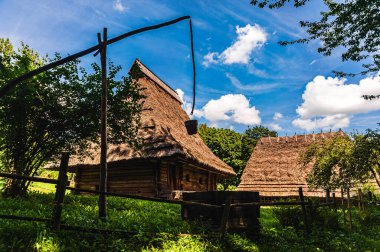 Mavi gökyüzüne karşı sazdan çatılı ve kuyusu olan 18. yüzyıldan kalma bir kulübe. Ukrayna 'nın batı bölgelerinde halk mimarisi manzaraları.