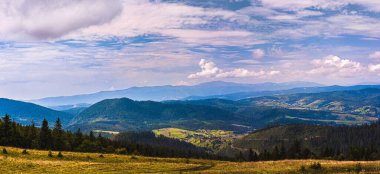 Karpatlar 'ın Panorama' sı. Dağlar ormanla kaplı. Mavi gökyüzü beyaz bulutlarla..