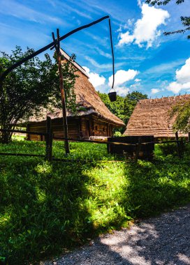 Mavi gökyüzüne karşı sazdan çatılı ve kuyusu olan 18. yüzyıldan kalma bir kulübe. Ukrayna 'nın batı bölgelerinde halk mimarisi manzaraları.