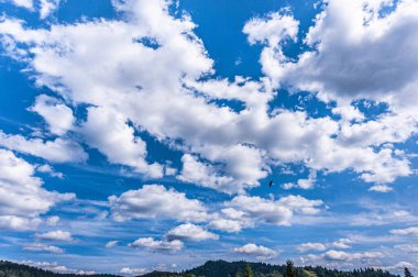 Karpatların üzerinde beyaz bulutlar olan mavi gökyüzü. Kabarık beyaz bulutlu parlak mavi gökyüzünün yatay görüntüsü. Uzayı kopyala..