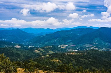 Karpatlar 'da yaz günü. Dağ manzarası. Ormanlar dağların yamaçlarında yetişir. Bulutlu güzel bir gökyüzü. Boşluğu kopyala.