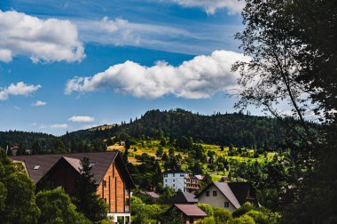 Karpatya bölgesindeki köy manzarası. Dağların üzerinde beyaz bulutlu güzel mavi bir gökyüzü var. Uzayı kopyala..