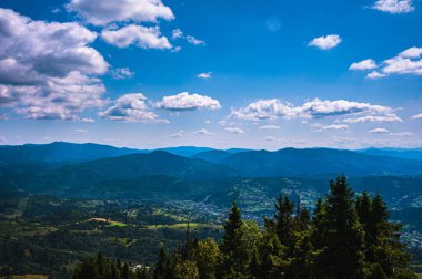 Karpatlar 'da yaz günü. Dağ manzarası. Ormanlar dağların yamaçlarında yetişir. Bulutlu güzel bir gökyüzü. Boşluğu kopyala.