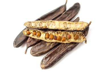 Kurumuş keçiboynuzu tohumlarıyla dolu bir grup beyaz arka planda izole edilmiş.