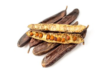 Kurumuş keçiboynuzu tohumlarıyla dolu bir grup beyaz arka planda izole edilmiş.