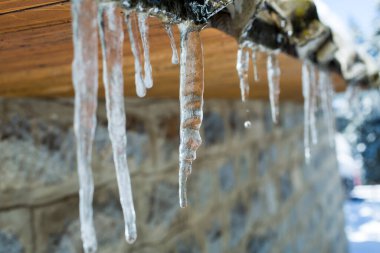 Kışın bir evin çatısında buz saçakları.