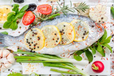 Limonlu taze çiğ solungaç balıklar, otlar, tahta tahtada tuz, beyaz ahşap arka plan. Sağlıklı gıda konsepti. Yiyecek çerçevesi. Balık gübresi.