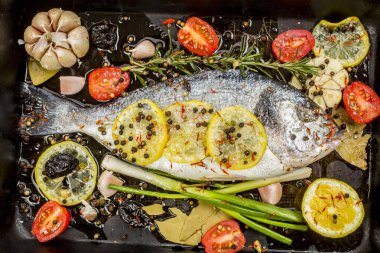 Lezzetli taze çipura ya da koyu arkaplanda dorade balığı. Aromatik otlu balık, limon, sarımsak, baharat ve sebzeler - sağlıklı yiyecek, diyet veya pişirme konsepti