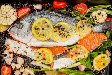 Koyu arkaplanda taze çipura ve somon balığı. Aromatik otlu, baharatlı ve sebzeli balıklar - sağlıklı yiyecekler, diyet veya yemek pişirme konsepti