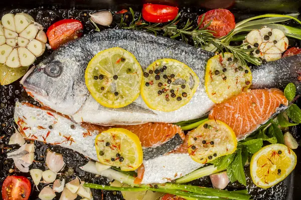 Koyu arkaplanda taze çipura ve somon balığı. Aromatik otlu, baharatlı ve sebzeli balıklar - sağlıklı yiyecekler, diyet veya yemek pişirme konsepti