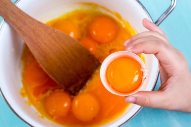 Yumurtayı kaseye kıran ellerin yakın çekimi.