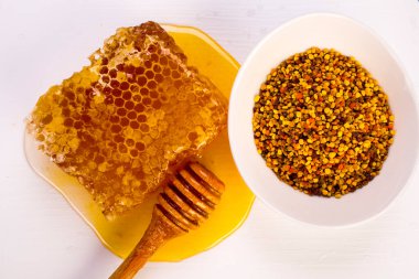 Tatlı bal peteği ve beyaz aşk ekmeği üzerinde ahşap çiseleyici