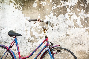 Eski, paslı bir bisiklet Pis bir duvara yaslanıyor 