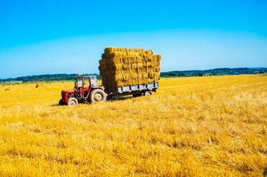Tarım karavanında saman dolu bir traktör..