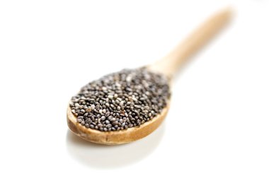 Tahta kaşıkta chia tohumları, beyaz arka planda izole edilmiş.