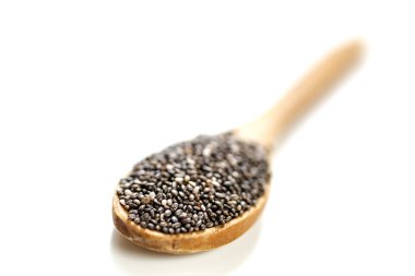 Tahta kaşıkta chia tohumları, beyaz arka planda izole edilmiş.