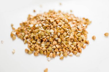 Ahşap kaşıkta pişmemiş karabuğday, beyaz arka planda birinci sınıf karabuğday inlemeleri.