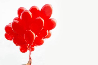 Beyaz üzerinde kırmızı balonlar tutan kız.