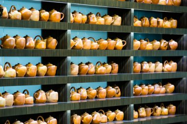 Raflarda bir sürü kahverengi çaydanlık var.