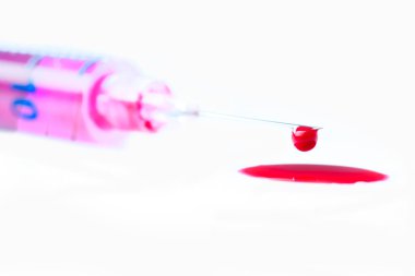 Şırıngada şırıngayla çıkarılmış kan, izole edilmiş beyaz arka planda kan damlaları.