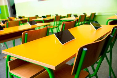 Sınıftaki masalarda dijital tabletler var.