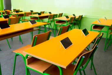 Sınıftaki masalarda dijital tabletler var.