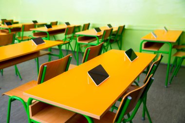 Sınıftaki masalarda dijital tabletler var.