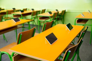 Sınıftaki masalarda dijital tabletler var.