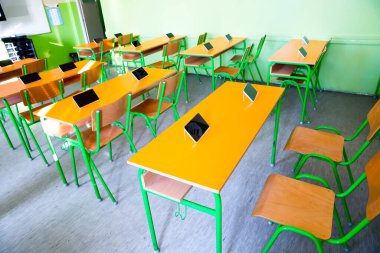 Sınıftaki masalarda dijital tabletler var.