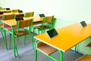 Sınıftaki masalarda dijital tabletler var.