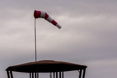 Bulutlu bir zemin üzerinde kırmızı ve beyaz rüzgar gülü