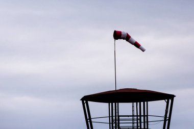 Bulutlu bir zemin üzerinde kırmızı ve beyaz rüzgar gülü