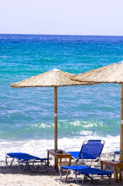 Kumsalda güneş yatakları ve saman şemsiyeleri.