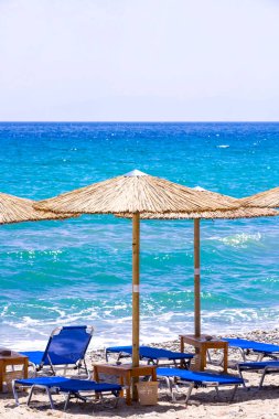 Kumsalda güneş yatakları ve saman şemsiyeleri.