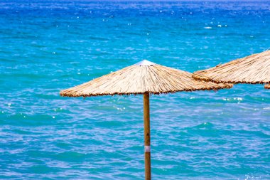 Kumsalda güneş yatakları ve saman şemsiyeleri.