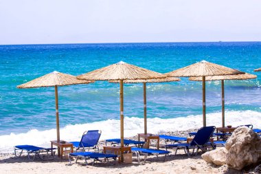 Kumsalda güneş yatakları ve saman şemsiyeleri.
