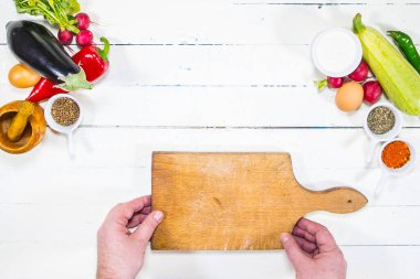 Ahşap bir masada taze sebze kesen eller.