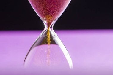 Kum saati mor ve siyah arkaplanda izole edilmiş, kopyalama alanı var..