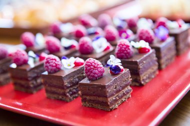 Ahududu ve yenilebilir çiçekli küçük çikolatalı kekler.  