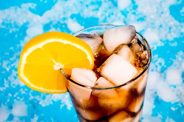 summer drink with ice and lemon on blue background
