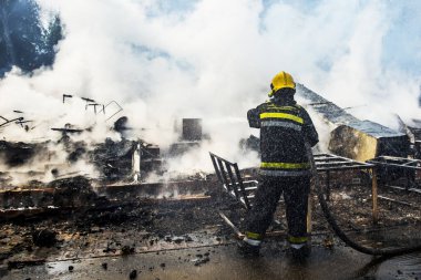 İtfaiyeci yangını suyla söndürüyor.