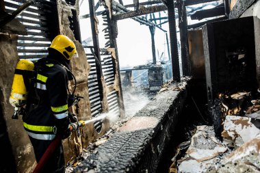 İtfaiyeci yangını suyla söndürüyor.