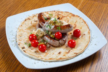 Domates ve baharatlı tortillada ızgara sosis.
