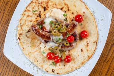 Domates ve baharatlı tortillada ızgara sosis.