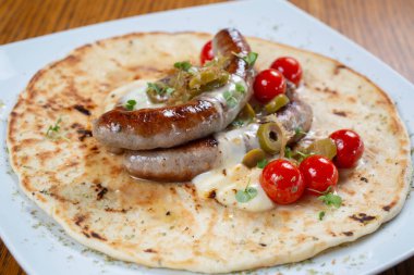 Domates ve baharatlı tortillada ızgara sosis.